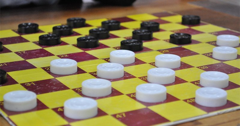 Tabuleiro de jogo de damas com as peças colocadas em cima