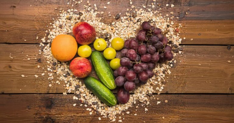 cereais, frutas e legumas frescos dispostos em uma tábua de madeira em forma de coração