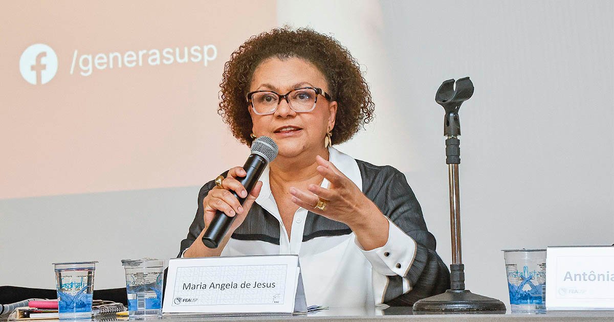 Mulher negra, cabelos encaracolados, até o pescoço e usando óculos