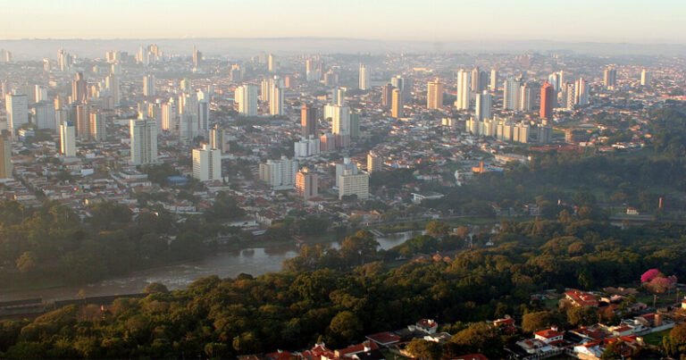 Imagem aérea deuma cidade cheia de prédios um rio e árvores
