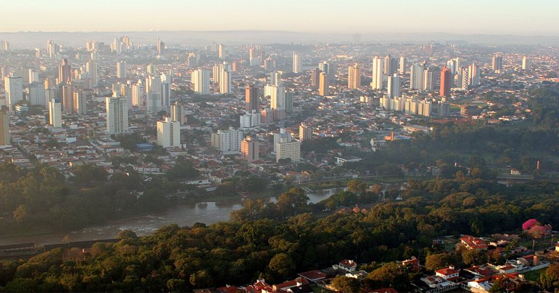 Imagem aérea deuma cidade cheia de prédios um rio e árvores