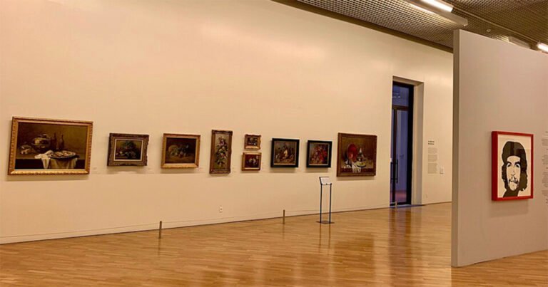 Imagem mostra uma sala de exposições da Pinacoteca de São Paulo, com vários quadros pendurados na parede