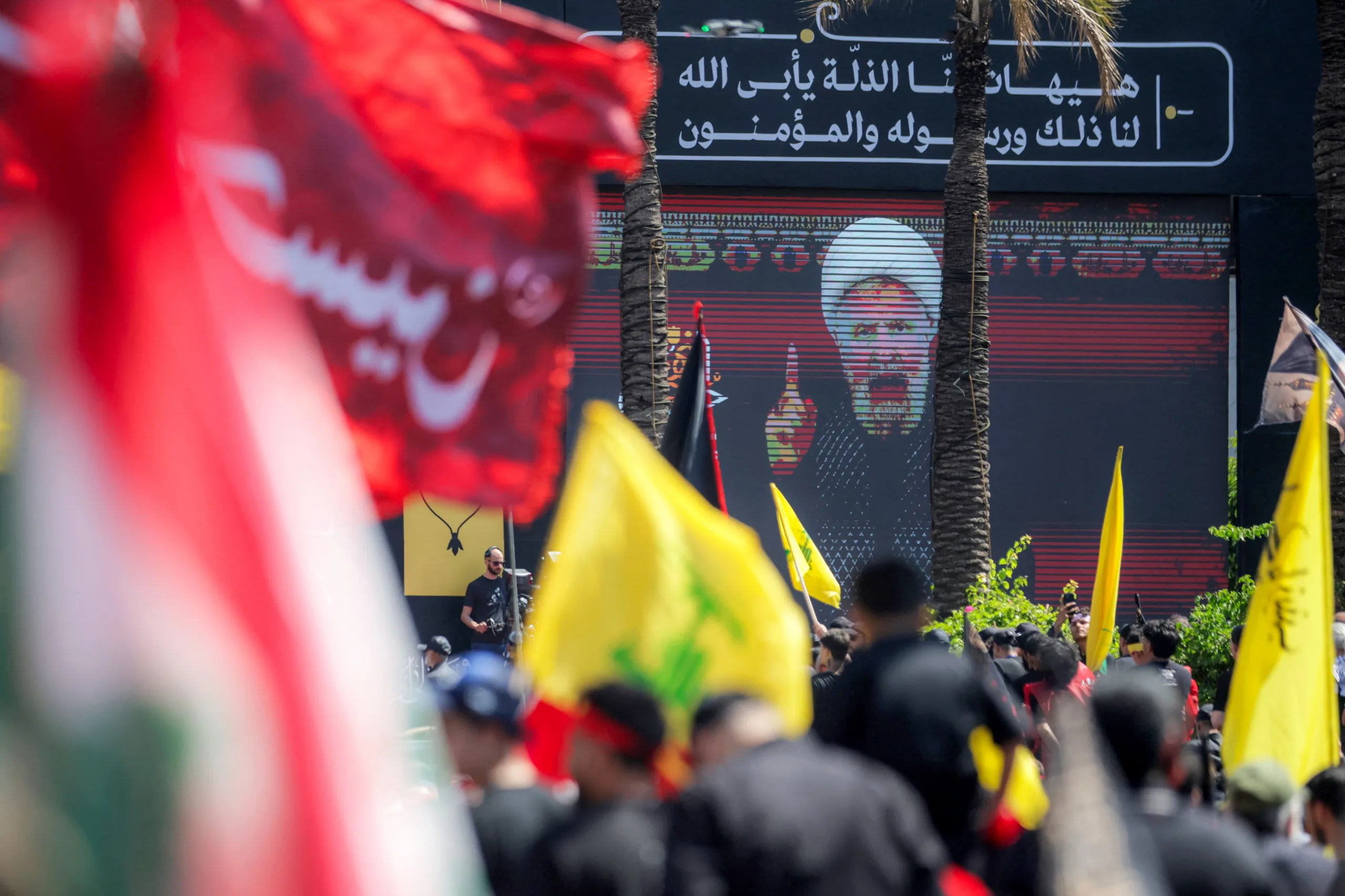 Uma multidão assiste à transmissão de um discurso de Naim Qassem, líder do Hezbollah