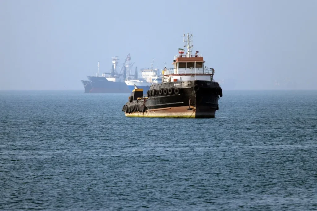 In this picture obtained from Iran's ISNA news agency on May 4, 2026, the Iran-flagged tugboat Basim sails near a ship anchored in the Strait of Hormuz off Bandar Abbas in southern Iran. Iran's Revolutionary Guards on May 4 denied that any commercial ships had crossed the Strait of Hormuz, after the US military earlier said two US-flagged merchant vessels had transited through the vital waterway.