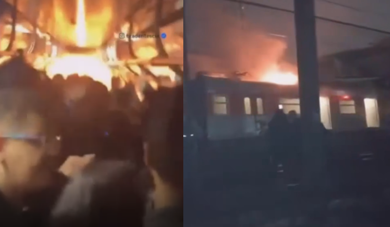 trem com passageiros pega fogo e pessoas se equilibram sobre trilhos