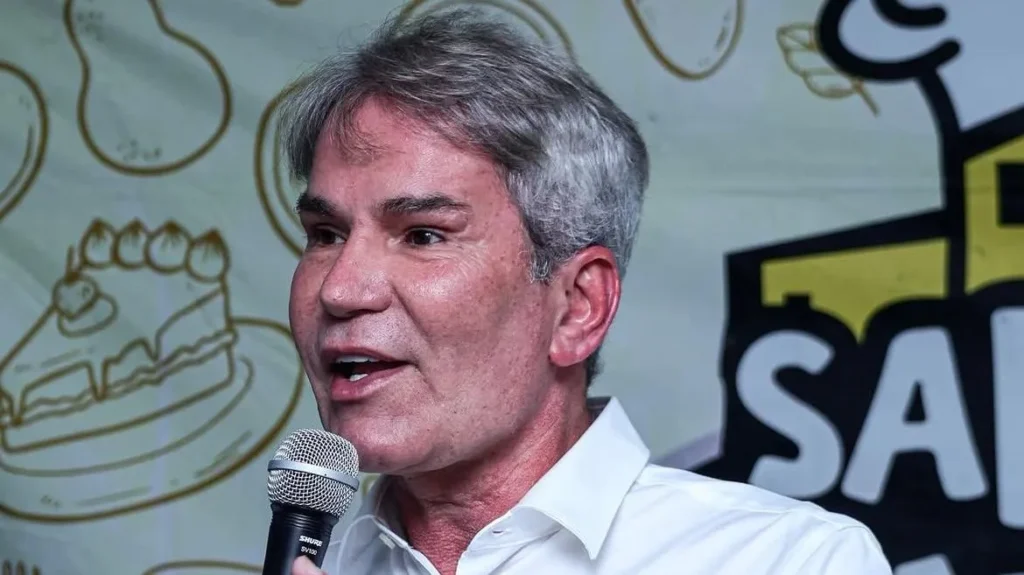 Márcio Pôncio, homem branco de cabelos grisalhos, fala ao microfone